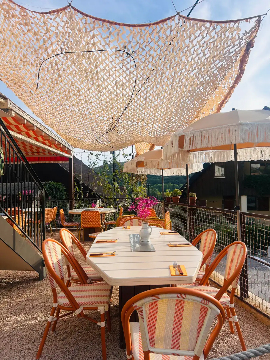 Parasols à franges et plantes grimpantes sur la terrasse du Petit Perroix